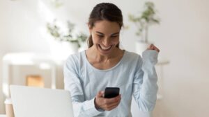 Happy woman looking at phone screen smiling