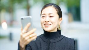 Woman Smiling at Phone Outdoors