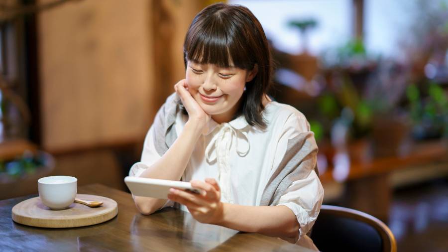 Woman Smiling at Phone in Cozy Cafe