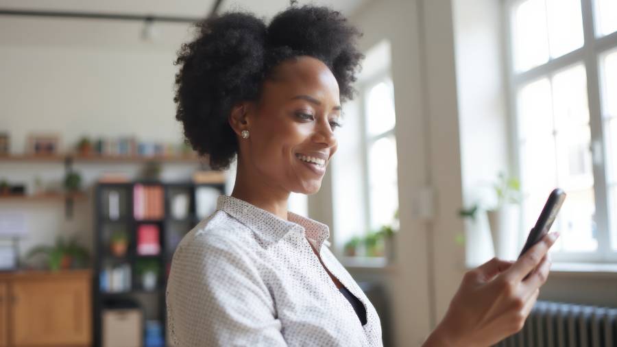 A woman is smiling while looking at her cell phone