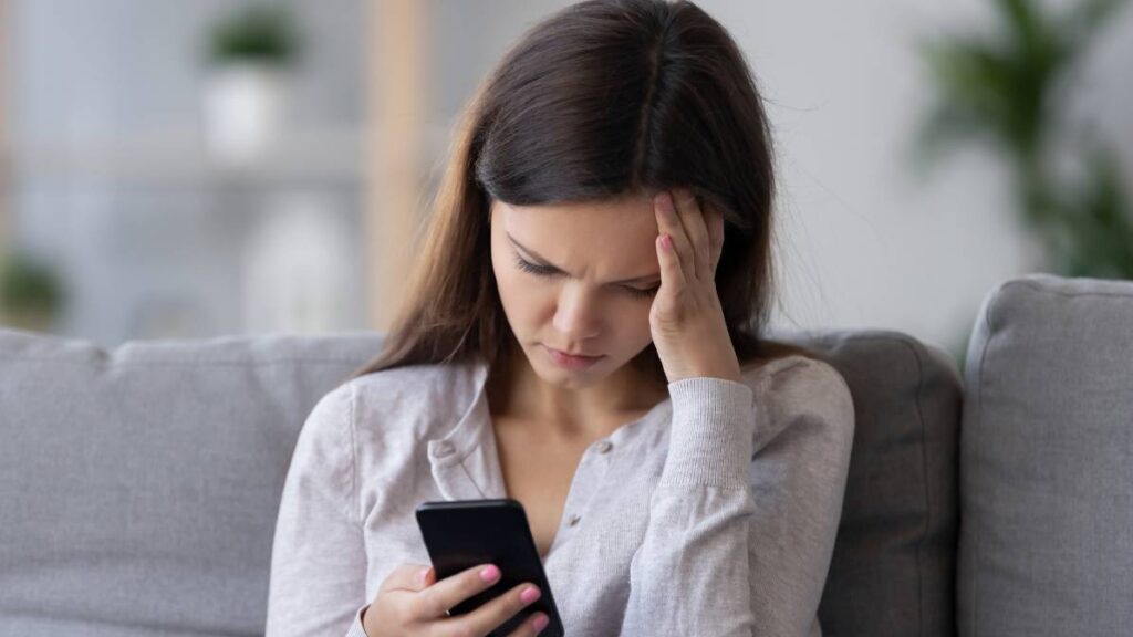 Lonely sad millennial woman feeling hurt heartbroken holding phone