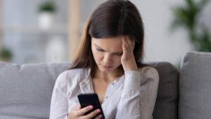 Lonely sad millennial woman feeling hurt heartbroken holding phone